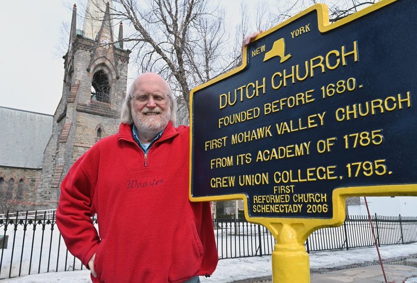 photo of County Historian Bill Buell standing next to the historical marker located at the First Reformed Church in the Stockade. 
