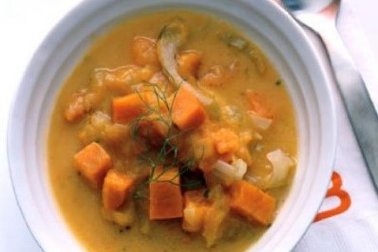 a photo of a white bowl filled with chunks of orange sweet potato in a Sweet Potato Soup.  